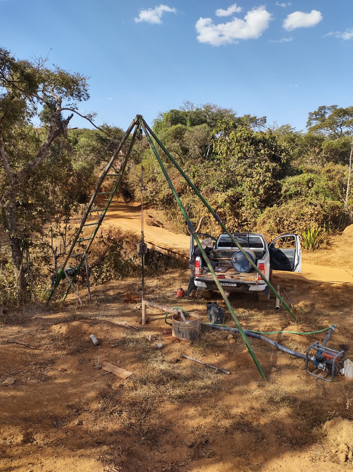 Equipe e equipamento de sondagem em terreno rural